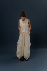 Pollera larga de lino color gris topo, de diseño amplio con volumen, movimiento y bolsillos delanteros. Cuenta con elástico en la cintura y detalles de pinzas y sobretelas en los laterales.