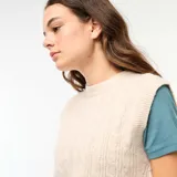 Chaleco de punto color beige con diseño trenzado, cuello redondo y sin mangas.
