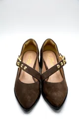 Zapato tipo Mary Jane de gamuza color marrón, con taco cuadrado medio y tira ajustable en el empeine con hebilla metálica dorada y detalles de ojalillos.