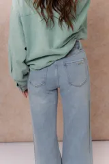 Pantalón de jean color arena con silueta wide leg, tiro medio-alto y costuras verticales delanteras que estilizan la figura. Cuenta con bolsillos funcionales y cierre frontal con doble botón.