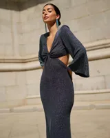 Vestido largo de fiesta color azul oscuro con lurex, escote en V, corte a la cintura y falda con caída. Mangas largas acampanadas.