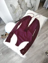 Body de manga larga en color bordó, confeccionado en lycra opaca con paneles frontales y puños de encaje floral. Presenta un diseño con escote profundo y espalda descubierta con tiras finas.