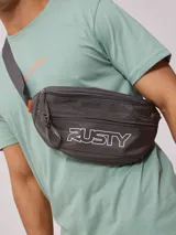 Riñonera de nylon color gris oscuro con cierre frontal y logo de la marca estampado en blanco. Cuenta con correa ajustable y etiqueta lateral con el nombre de la marca.