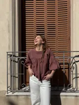 Blusa color chocolate de diseño holgado, con cuello redondo, frunce frontal y mangas abullonadas con puños ajustados.