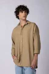 Camisa de manga larga confeccionada en lino, color verde oliva, con cuello clásico y cierre frontal de botones.