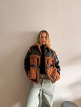 Campera negra de cuero sintético con cuello, solapas, puños y bolsillos de corderito color marrón.