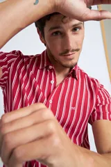 Camisa de manga corta con diseño a rayas verticales en color azul marino y blanco. Presenta cuello clásico, cartera abotonada frontal y logo bordado en el pecho. Posee un corte slim fit.