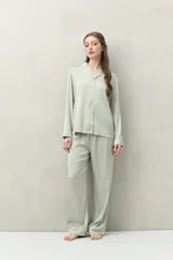 Camisa de pijama color verde menta, de silueta clásica y tacto sedoso. Confeccionada en tejido satinado con leve elasticidad, presenta cuello camisero, cierre frontal con botones y detalles de vivo blanco que realzan el diseño.