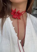 Gargantilla roja con dije de flor de porcelana y tiras finas para atar.