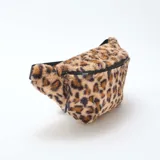 Riñonera de textura suave tipo peluche con estampado animal print de leopardo. Cuenta con cierre superior negro y correa ajustable.