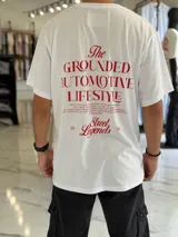 Remera oversize blanca de manga corta, con gran estampado tipográfico en color rojo en la espalda con la leyenda "The Grounded Automotive Lifestyle".