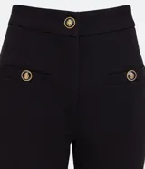 Pantalón flare negro de punto roma, con cintura alta, bolsillos delanteros con botones metálicos estilo escudo y cierre por cremallera y botón.