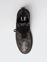 Borcego de punta redonda con efecto cuero desgastado, cordones y tira de velcro frontal. Cuenta con suela track y herrajes metálicos.