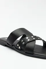 Sandalias bajas negras de símil cuero, con tiras asimétricas y apliques de tachas.
