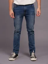 Jean de corte slim fit con cintura media, confeccionado en denim azul con efecto de lavado desgastado.