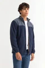 Campera de polar con cierre frontal completo, cuello alto y diseño bicolor en gris y negro. Cuenta con bolsillos laterales y puños elásticos.