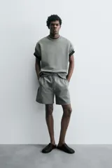 Bermuda de algodón color beige claro, corte relajado (relaxed fit), con cintura elástica ajustable mediante cordón y bolsillos laterales y trasero de plastrón.