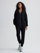 Campera negra de corte holgado con cierre bidireccional, cuello alto y bolsillos frontales.