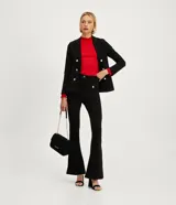 Pantalón flare negro de punto roma, con cintura alta, bolsillos delanteros con botones metálicos estilo escudo y cierre por cremallera y botón.