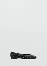 Zapato tipo bailarina color negro con diseño troquelado decorado con ojales metálicos plateados, punta redonda y suela plana.