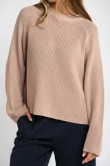 Sweater de algodón color beige, de punto acanalado, cuello redondo y manga larga con corte raglán.