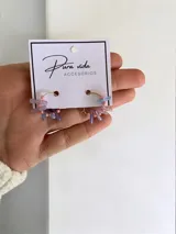 Aros tipo argolla decorados con pequeñas cuentas rosadas y piezas alargadas de cristal en tonos violeta y azul.