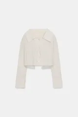 Camisa corta de manga larga con cuello solapa, confeccionada en tejido con efecto arrugado. Presenta cierre frontal con botones y forro interior combinado con tejido semitransparente.