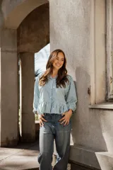 Camisa de algodón a rayas verticales en color verde y blanco, con cuello camisero, mangas largas y un detalle de volado en el ruedo que le otorga una silueta acampanada.