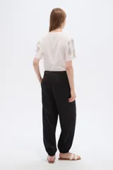 Pantalón de poliéster color negro, de tiro alto y corte holgado con frunces en los tobillos.