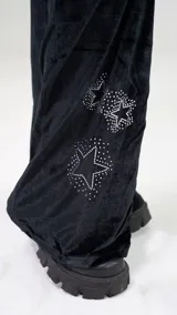 Pantalón de jogging de terciopelo negro con corte slim fit, cintura elástica con cordón ajustable y detalle de estrellas formadas por brillos aplicados en la pierna.