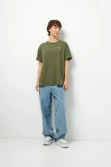 Remera negra de corte oversize con cuello redondo y manga corta. Presenta un pequeño estampado dorado en el pecho con la frase "love earth" y un símbolo de hojas.