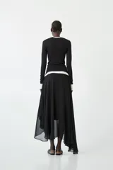 Falda maxi negra de tiro bajo con silueta amplia y largo asimétrico, confeccionada en poliéster.