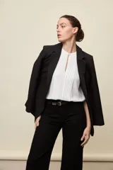 Blazer negro de líneas clásicas y silueta sastrera, con solapas y estructura definida.