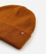 Gorro de punto tejido en color verde oliva, con diseño de borde plegado y una pequeña etiqueta rectangular aplicada en el frente.