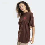 Remera blanca de corte oversized, con cuello redondo y mangas cortas. Presenta un pequeño estampado en el pecho con el logo de la marca Reef en color rojo y detalles de estrellas.