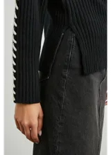 Sweater negro de punto con cuello alto y bordados blancos en sisas y mangas.