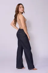 Jean de corte wide leg y tiro bajo, color azul oscuro, con costuras laterales desplazadas hacia el frente y cierre frontal con botón.