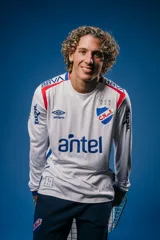 Camiseta de fútbol Umbro del Club Nacional de Football, modelo Home de manga larga. Diseño blanco con detalles en rojo y azul en los hombros y puños. Incluye logo de Umbro, escudo del club y detalles conmemorativos en el pecho.