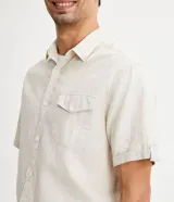 Camisa de hombre de manga corta color marrón, confeccionada en lino y algodón. Presenta cuello clásico, botonadura frontal, bolsillo en el pecho y mangas con botón para enrollar.