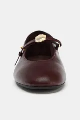Zapato tipo bailarina de cuero color bordó, con tira ajustable en el empeine, detalle metálico y punta redonda.