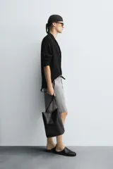 Sobrecamisa de punto negro de corte relajado, con cuello solapa y manga larga. Presenta cierre frontal de botonadura y acabados en rib.