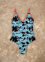 Malla entera celeste con estampado de flores negras y terminaciones en color naranja.