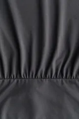 Top corto de manga larga en punto elástico de color gris, con corte holgado, cuello redondo y hombros caídos. Presenta bajo ancho de ajuste ceñido con costura fruncida.