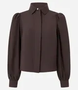Camisa de crepé color celeste, con cuello inglés, manga larga abullonada y cierre frontal oculto con botón diferenciado en el cuello.