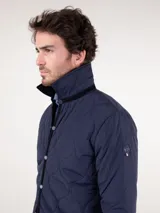Cazadora acolchada azul marino con cuello de pana negro, cierre con botones a presión y bolsillos laterales.