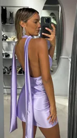 Vestido corto de satén color lila, con diseño de cuello halter y escote profundo en V. Presenta un corte ajustado y fluido, ideal para eventos nocturnos.