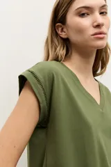 Remera verde oliva con cuello en V, mangas cortas y detalle de vainillas en las costuras de las mangas y el ruedo.