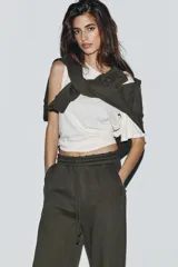 Pantalón de tiro medio con pierna ancha, confeccionado en tejido lavado. Presenta cintura elástica ajustable con cordones, bolsillos laterales y bolsillos traseros decorados con estrellas y aplicaciones de tachas. El diseño cuenta con terminaciones desflecadas en el ruedo.