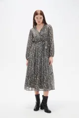 Vestido midi de corte evasé con estampado animal print en tonos oscuros. Presenta escote en V cruzado, mangas largas con puños y falda con volados escalonados.