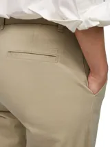 Pantalón chino color beige de corte slim, con cierre de botón y cremallera, cuatro bolsillos y logo de Tommy Hilfiger bordado en el bolsillo trasero.